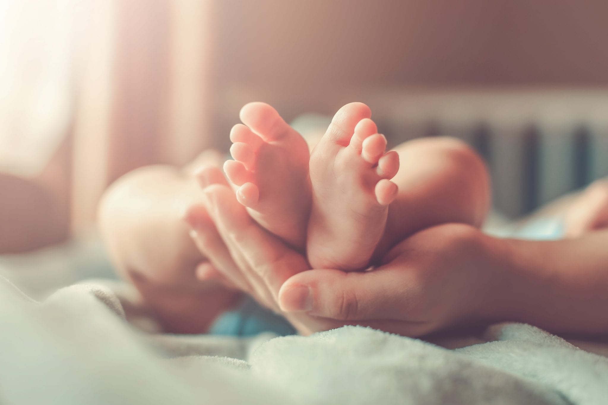 Image of a baby's feet held by a mother's hands