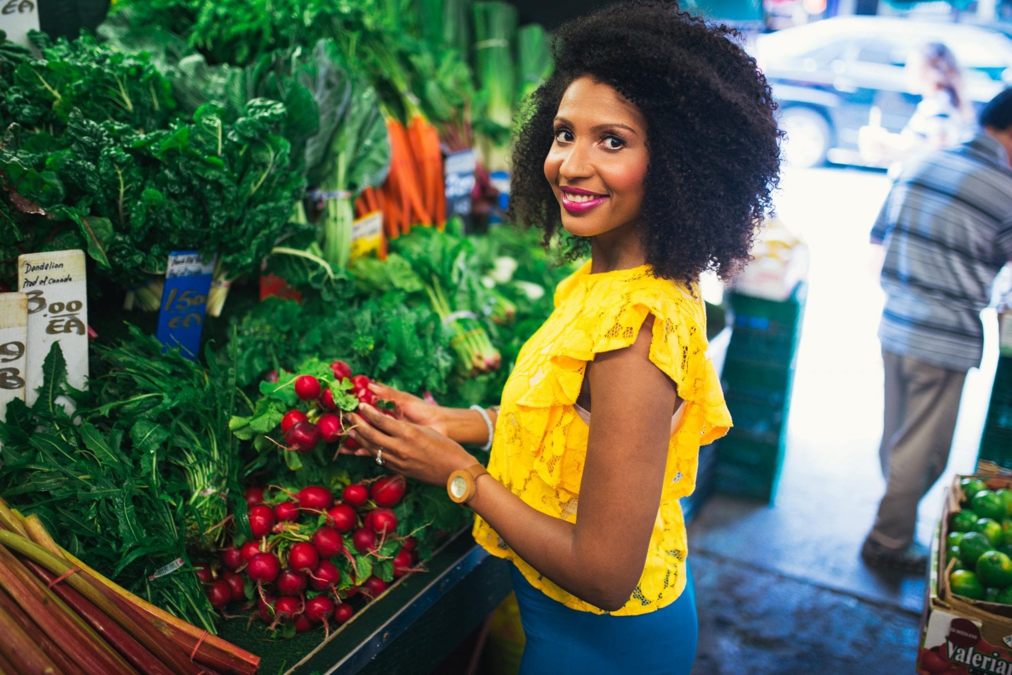 Woman with yellow shirt next to an aisle of fresh produce vegetables