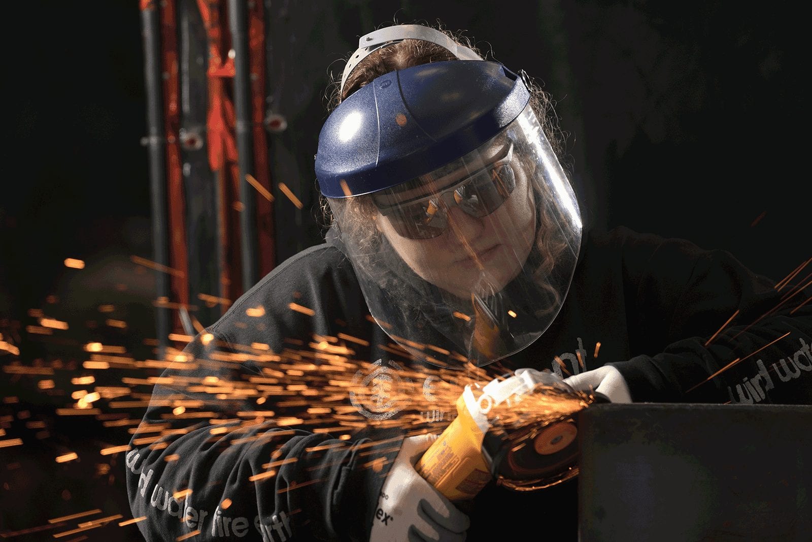 Image of woman using a power tool to cut steel
