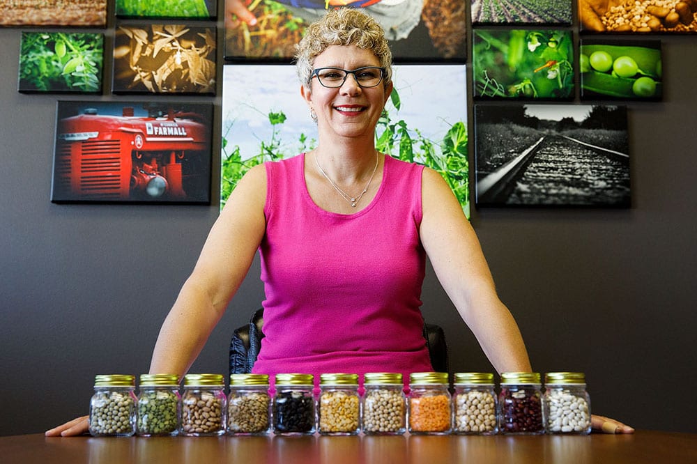 Debra McLennan standing behind jars of different pulse varieties
